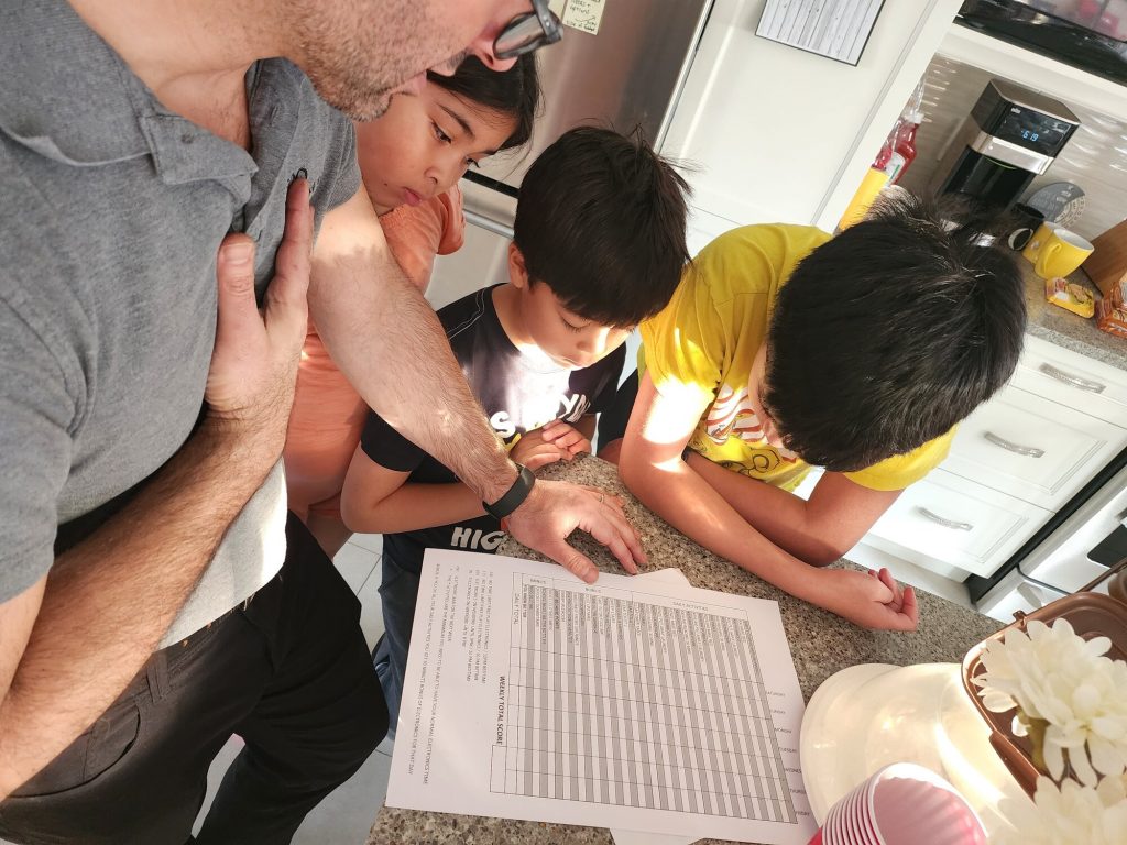 a dad showing and explaining a chore chart to his kids