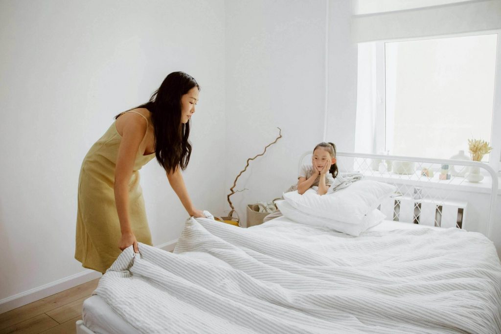 a mother making her bed with her daughter