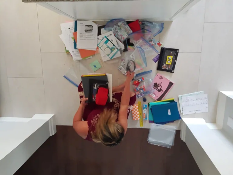 Top view of a woman on the floor trying to organize school supplies